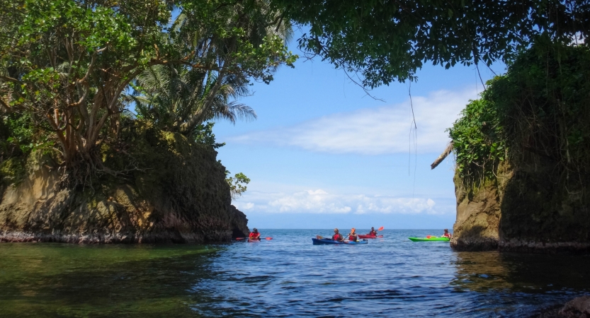 Kayaks are paddled between two pieces of land.